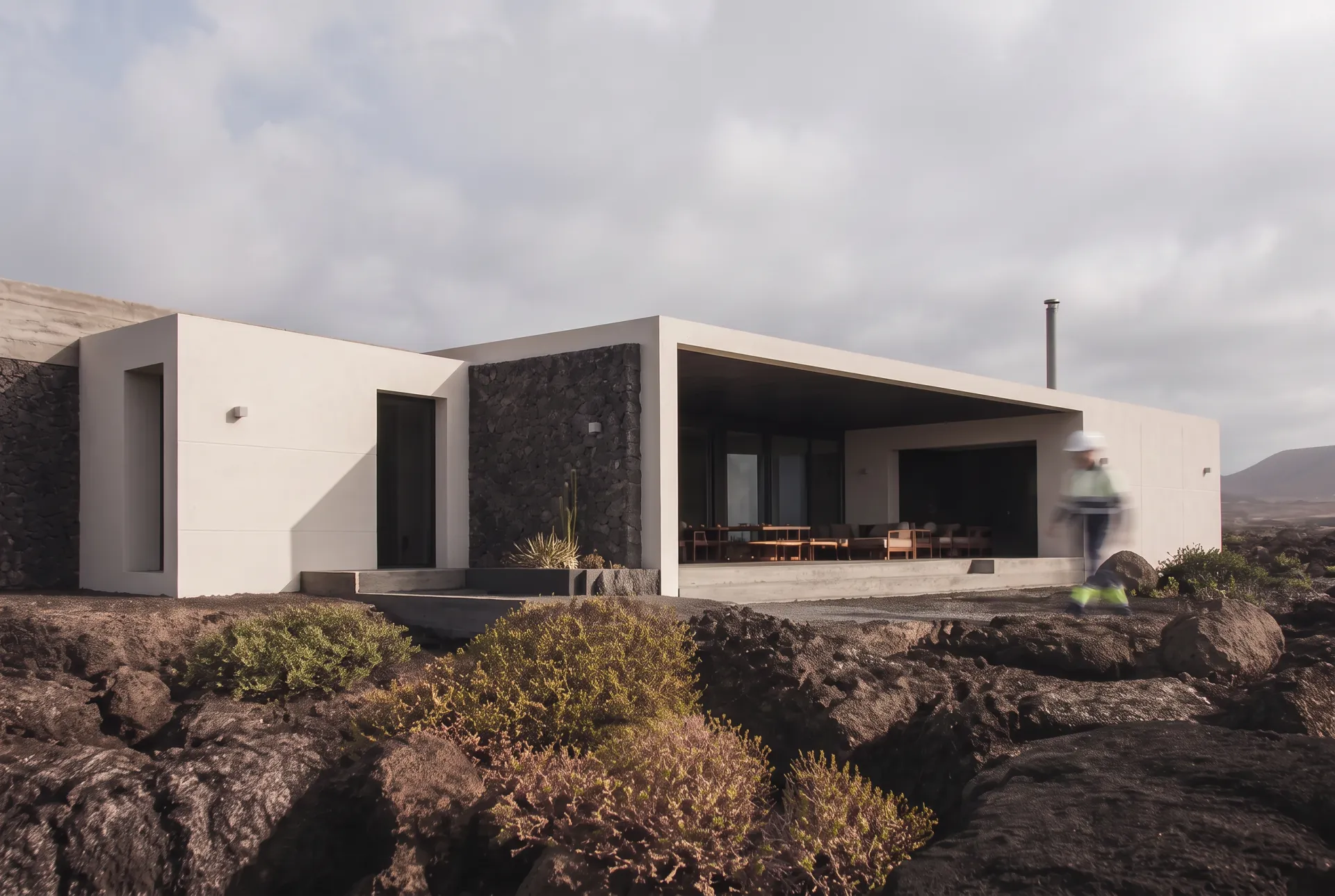 Vivienda contemporánea de hormigón y piedra volcánica integrada en un paisaje atlántico árido
